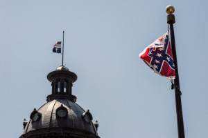COLUMBIA, SC - JUNE 18:  The South Carolina and American flags fly at half mast as the Confederate flag unfurls below at the Confederate Monument June 18, 2015 in Columbia, South Carolina. Legislators gathered Thursday morning to honor their co-worker Clementa Pinckney and the eight others killed yesterday at Emanuel AME Church in Charleston, South Carolina. (Photo by Sean Rayford/Getty Images)