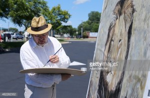 BLOOMINGTON, MN - JULY 29:  Painter Mark Balma paints a portrait of Cecil the lion to donate to anti-poaching efforts in the parking lot of Dr. Walter Palmer's clinic on July 29, 2015 in Bloomington, Minnesota.  (Photo by Adam Bettcher/Getty Images)