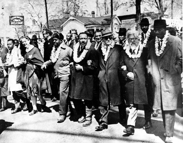 Dr. Martin Luther King Jr. links arms with other civil rights leaders as they begin the march to the state capitol in Montgomery from Selma, Ala. on March 21, 1965. The demonstrators are marching for voter registration rights for blacks. Accompanying Dr. Martin Luther King Jr. (fourth from right), are on his left Ralph Bunche, undersecretary of the United Nations, Rabbi Abraham Joshua Heschel, and Rev. Fred Shuttlesworth. They are wearing leis given by a Hawaiian group.  (AP Photo)